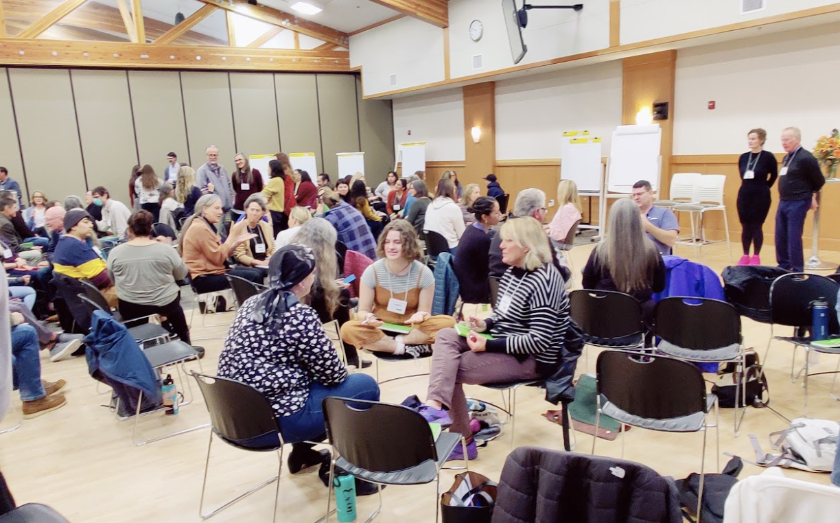 Group of people sitting and speaking with one another in small circles in chairs.