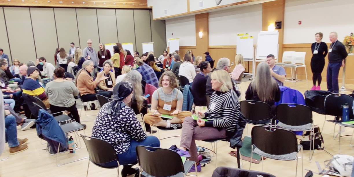 Group of people sitting and speaking with one another in small circles in chairs.
